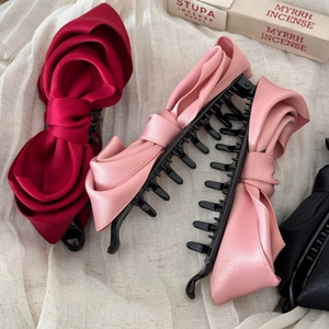 Macro view of satin bow hair banana clips in burgundy, pink and black on linen