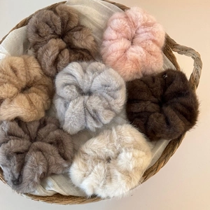 Macro shot of fluffy faux fur scrunchies in various autumn colors on linen fabric