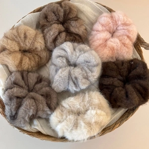 Macro detail of seven plush faux fur oversized scrunchies in soft autumn and winter colors