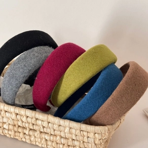 Close-up of thick wool knit headbands in six colors displayed in a woven basket