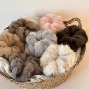 Plush faux fur scrunchies in various Morandi colors set in a woven basket