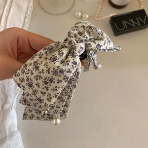 Detail showing floral fabric bow hair clip with elegant pearl and silver pendants