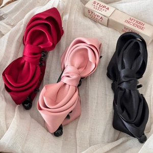 Three classic French satin bow hair clips in wine red, pink and black set on fabric