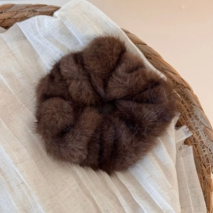 Close-up of soft brown plush scrunchie with fluffy texture for autumn and winter styles