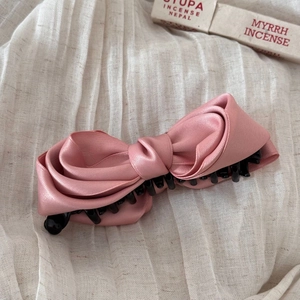 Close-up of a pink satin bow banana clip with non-slip teeth for elegant hairstyles