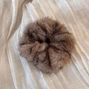 Close-up of a brown plush oversized scrunchie showing soft faux fur texture detail