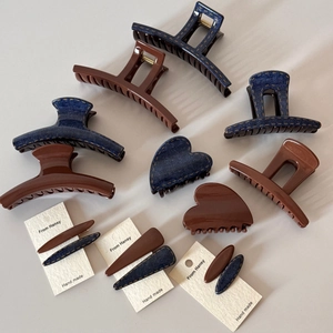 Detail of denim and acrylic hair clips showing yellow stitching and texture