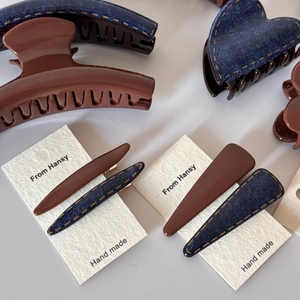 Detail view of denim fabric hair clips and matte brown claw clips with yellow stitching