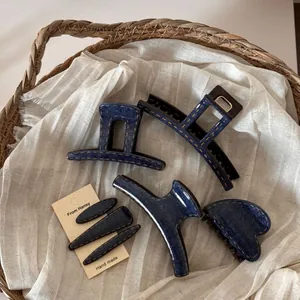 Detail of dark blue denim texture hair claws and clips with contrast yellow stitching