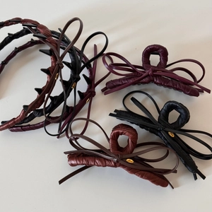 Detail of Korean style leather bow hair clips in black, brown, and wine red with gold charms