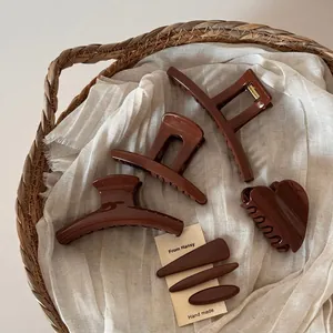 Brown mocha hair claw clips set and long hair pins on white linen and wicker background