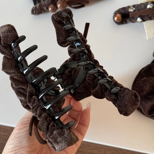 Detail of a large hair claw clip wrapped in dark chocolate brown pleated velvet fabric