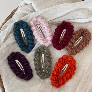 Dettaglio di fermagli per capelli in lana all'uncinetto in sette colori su lino