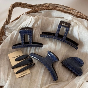 Detailed view of blue denim hair clips set with yellow contrast stitching in a basket