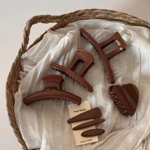 Deep brown hair claw set with matte finish and clips in a vintage woven basket