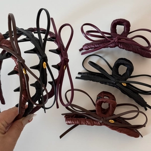 Detailed macro view of high-end leather bow hair clips with Love metal accents