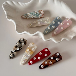 Lot de barrettes en acétate avec fleurs 3D sur un plateau en céramique élégant