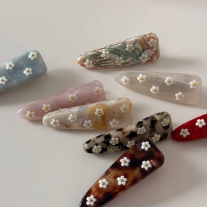 Vue détaillée de barrettes en acétate avec petites fleurs blanches en relief 3D