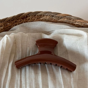Detailed view of the large dark brown glossy resin hair claw clip on white linen