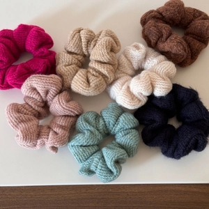 Dettaglio di sette elastici scrunchie in maglia con texture morbida e trama intrecciata