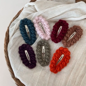 Dettaglio di sette fermagli per capelli colorati fatti a mano in un cestino