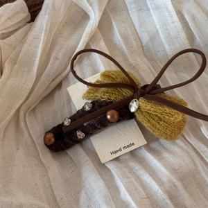 Detail of coffee velvet hair claw clip with yellow mohair bow and pearl accents