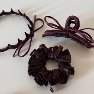 Detail view of burgundy leather hair accessories set including bow claw clip and scrunchie