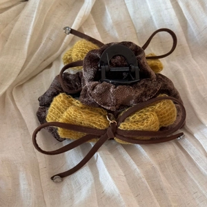 Macro view of dark brown and yellow velvet bow hair claw clip on beige fabric