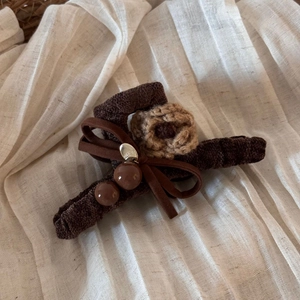 Detail of velvet bow hair claw with crochet flower and resin beads on soft fabric