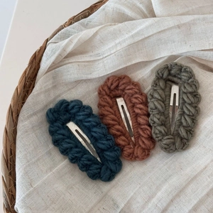 Dettaglio di tre fermagli per capelli fatti a mano all'uncinetto in toni vintage