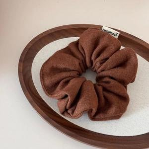Detail of wool fabric scrunchie in coffee brown with Happiness woven label tag