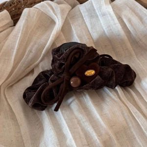 Detail of a large velvet hair claw clip with handmade heart charm and bow accent