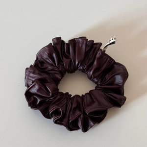 Close-up of deep burgundy faux leather scrunchie with soft folds and elegant texture