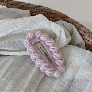 Dettaglio di un fermaglio per capelli rosa lavorato a maglia con lana e base in metallo
