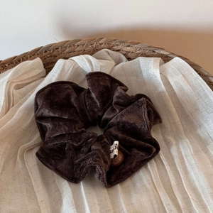 Close-up of velvet large hair scrunchie with decorative bead in a cozy woven basket