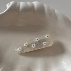 Détail d'une pince à cheveux en acétate nacré avec motifs de fleurs blanches