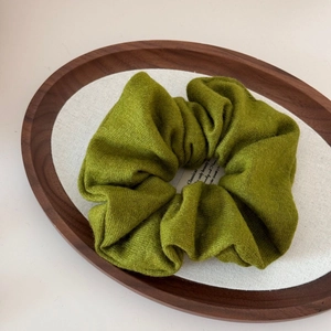 Macro detail of mustard green knit wool scrunchie showing soft textured plush fabric