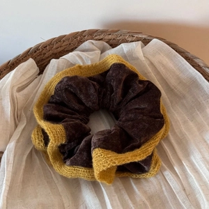 Detail of dark brown velvet scrunchie with yellow knitted lace edges in a basket