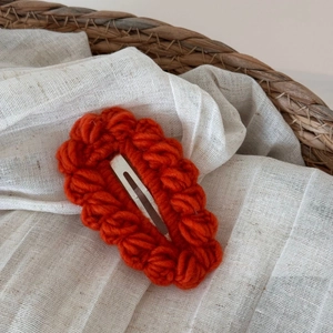 Dettaglio di un fermaglio per capelli in lana all'uncinetto color terracotta caldo