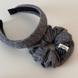 Détail d'un ensemble serre-tête et chouchou en maille grise avec breloque cœur et étiquette