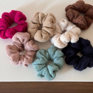 Dettaglio di sette elastici scrunchies in maglia colorata con texture morbida