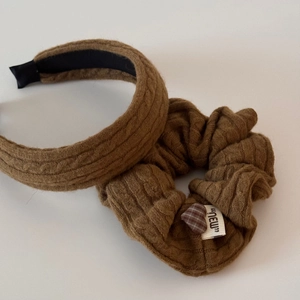 Détail du bandeau tricoté marron foncé et du chouchou avec motif de tresse et étiquette