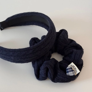 Détail d'un bandeau et chouchou en maille torsadée bleu marine avec breloque cœur