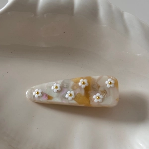 Détail de la pince à cheveux en acétate marbré avec fleurs 3D blanches et perles dorées