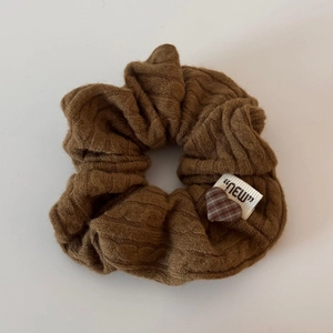 Détail du chouchou en maille marron avec étiquette NEW et breloque cœur à carreaux