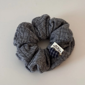 Détail du bandeau en maille grise avec un patch cœur à carreaux bleus et étiquette
