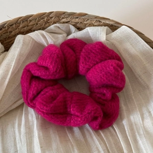 Dettaglio di elastico per capelli in maglia rosa con trama a coste su lino bianco