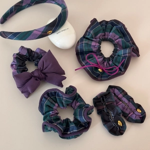 Detail view of purple and blue plaid fabric scrunchies with handmade gold tag detail