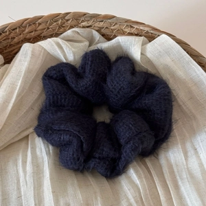 Dettaglio di scrunchie in maglia blu scuro con morbida trama in mohair su tessuto