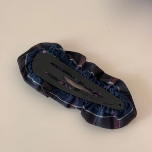 Detail view of the metal BB clip back showing blue plaid fabric and secure closing mechanism